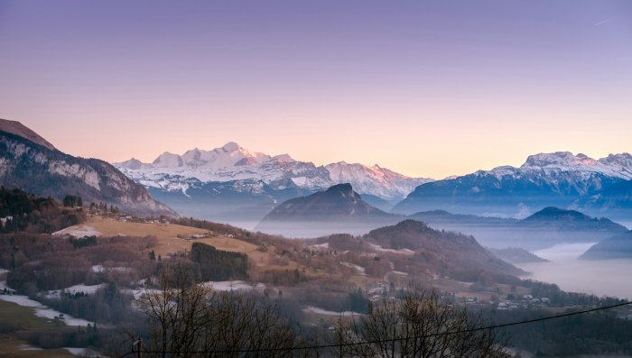 Snowy mountain range at sunrise with valley fog