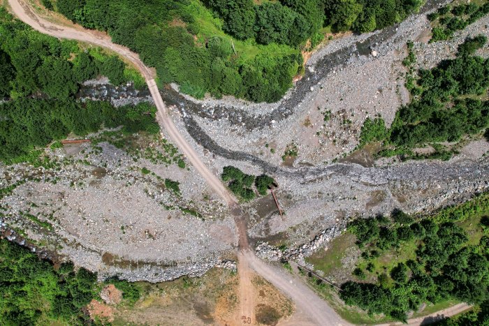 Aerial view of a dirt road crossing a rocky riverbed