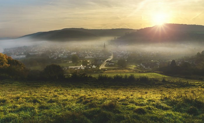 Foggy valley landscape with village at sunrise