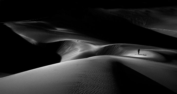 Lone person walking on desert sand dunes