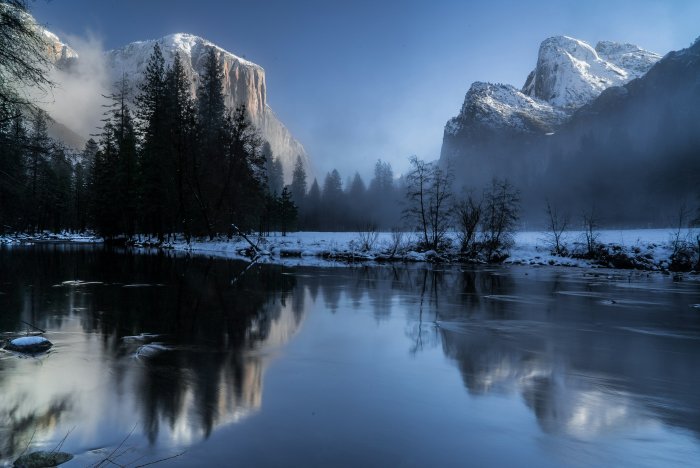 Snowy mountains reflected in a calm river during winter