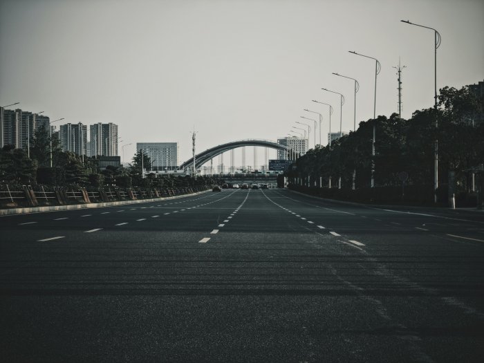Empty city street leading to a distant arched bridge