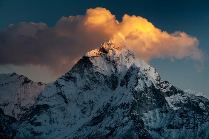 Snow-covered mountain peak with golden clouds at sunset