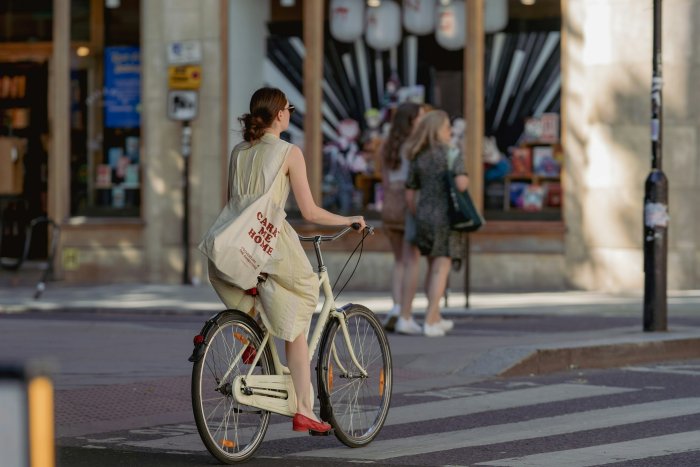 Woman in Yellow Dress Riding a Bicycle on City Street