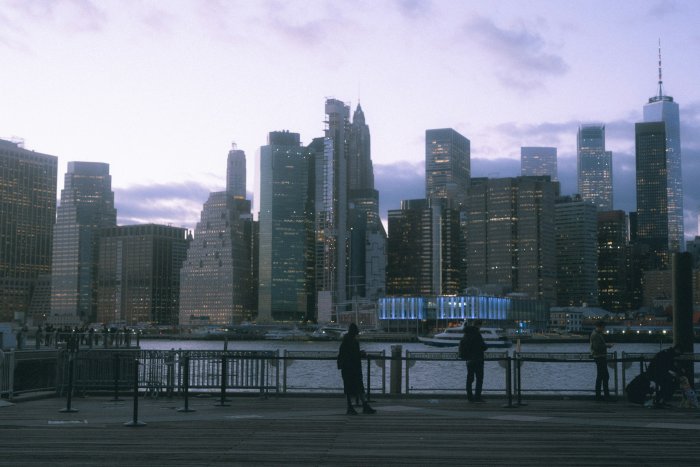 People on a pier overlooking the Manhattan skyline