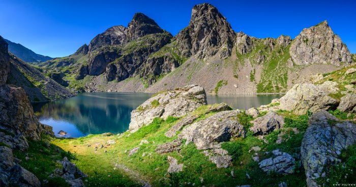 Mountain Lake Surrounded by Rocky Peaks and Green Slopes