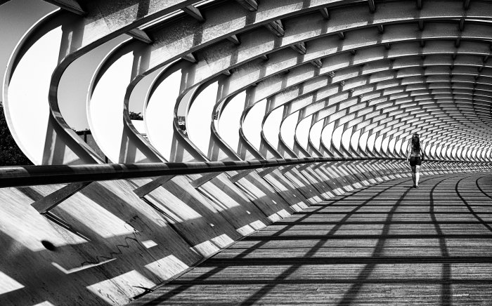 Woman Walking on Curved Modern Pedestrian Bridge