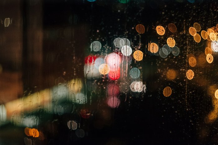 Raindrops on window with colorful bokeh city lights