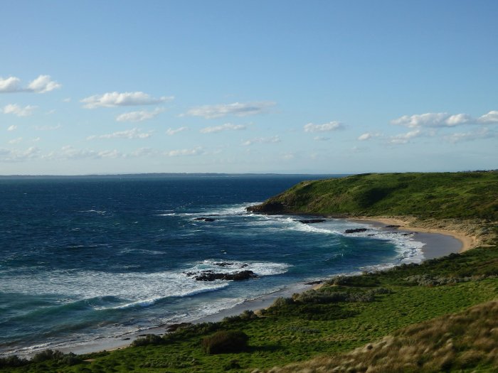 Green hills and sandy beach along the blue ocean
