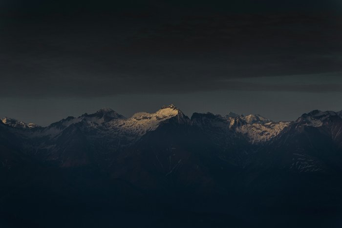 Snow covered mountain range under dark sky