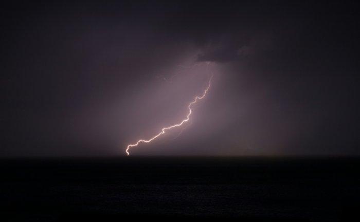 Lightning bolt striking the ocean at night