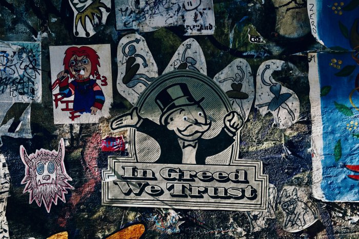 Mr. Monopoly and Chucky stickers on a graffiti wall