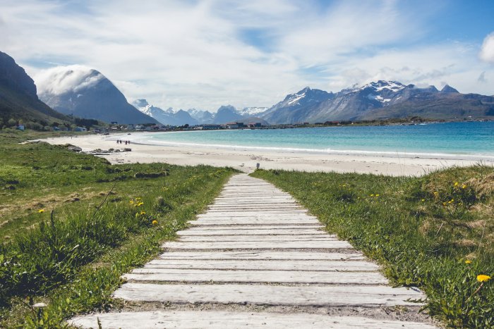 Wooden boardwalk leading to a beach with mountain backdrop