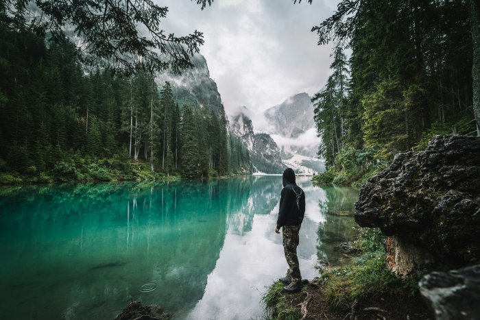 Man standing by a turquoise alpine lake
