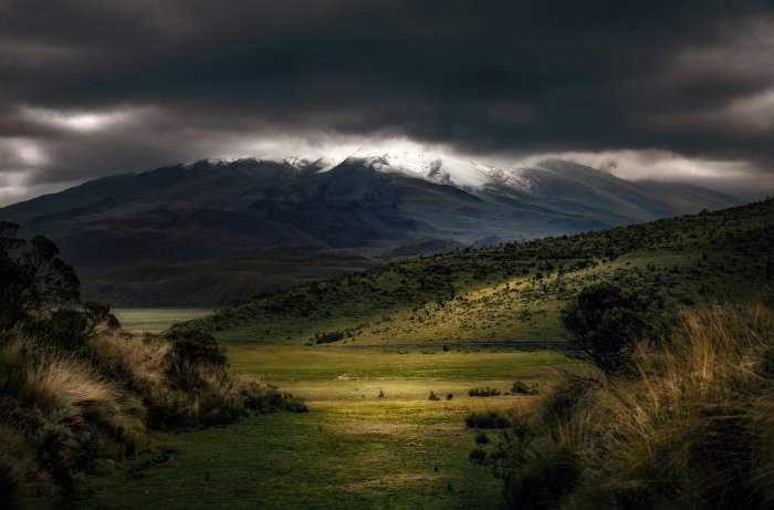 Dramatic storm clouds over a green mountain valley