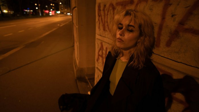 Blonde woman leaning against a graffiti wall at night