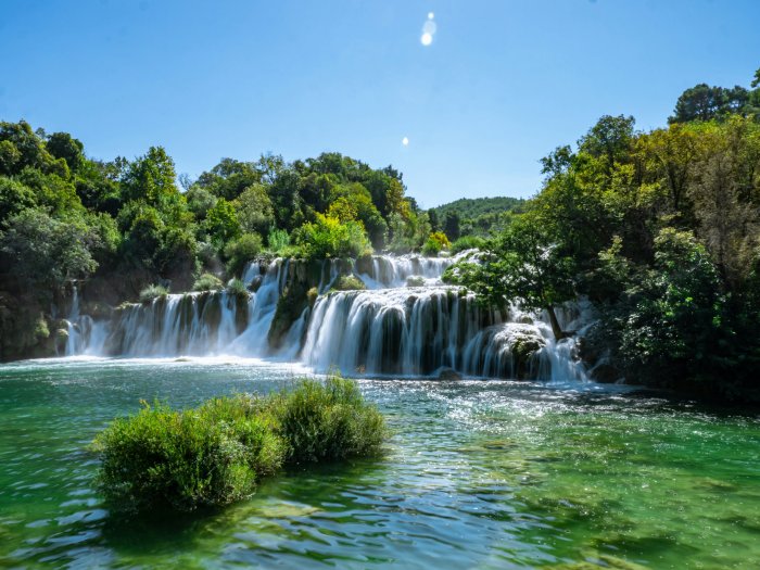 Cascading waterfall flowing into a clear green pool