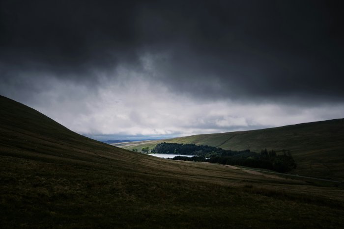Overcast sky above rolling hills and a distant lake