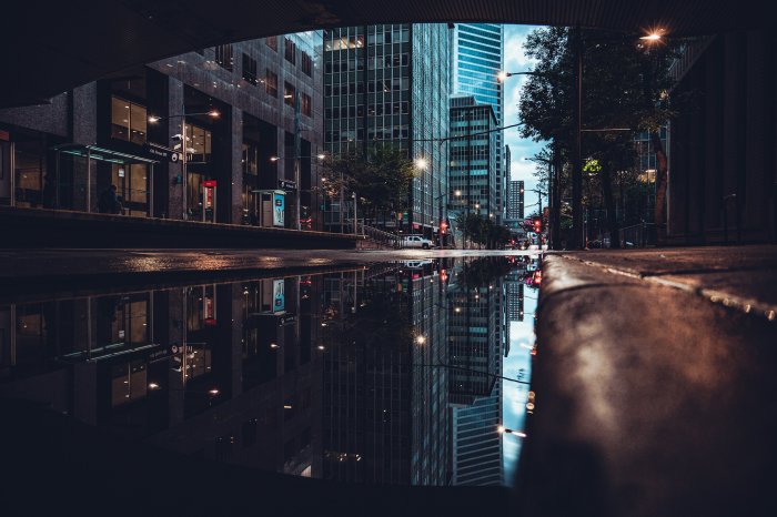 Urban street puddle reflecting tall city buildings