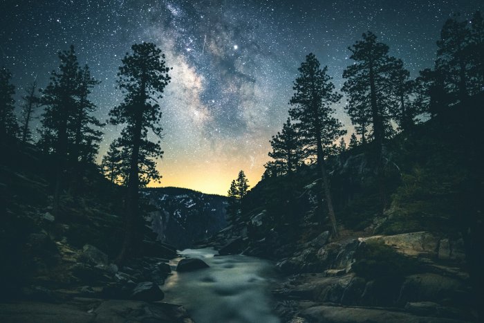 Milky Way galaxy over a river in a pine forest