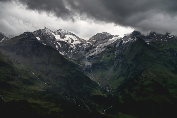Snow-capped mountain peaks under dark storm clouds