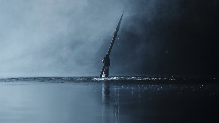 Arm holding spear emerging from water in Camp Miasma