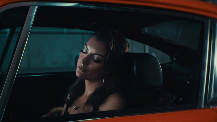 Woman with closed eyes inside an orange car in Singer