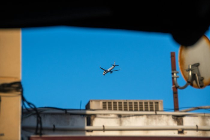 Airplane flying in a clear blue sky over buildings