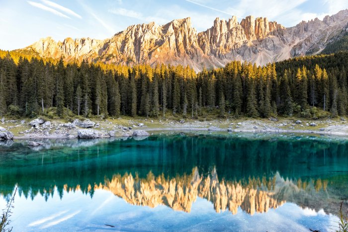 Turquoise alpine lake reflecting mountains and pine forest