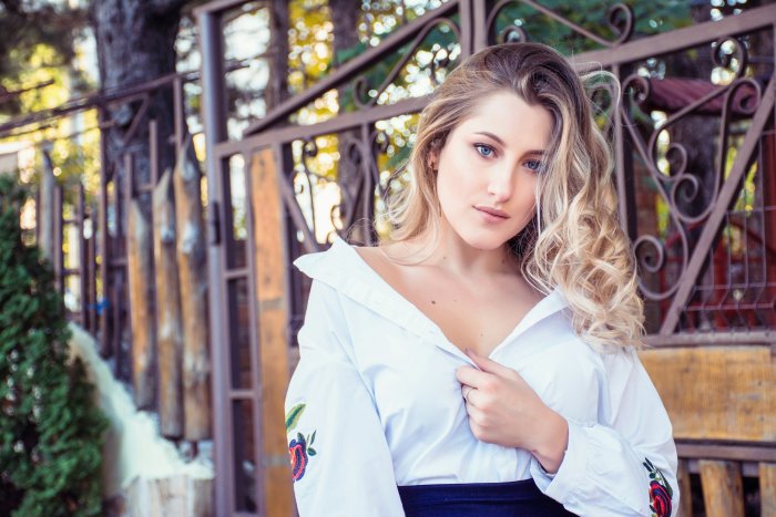 Blonde woman posing in front of a metal gate