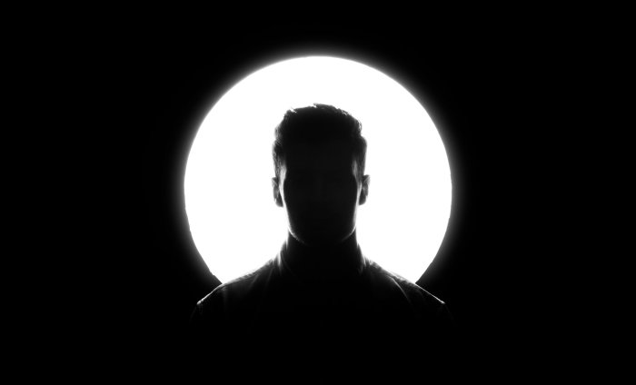 Silhouette of a man against a bright circular light