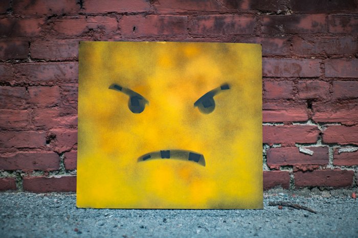 Angry face stencil art on yellow board