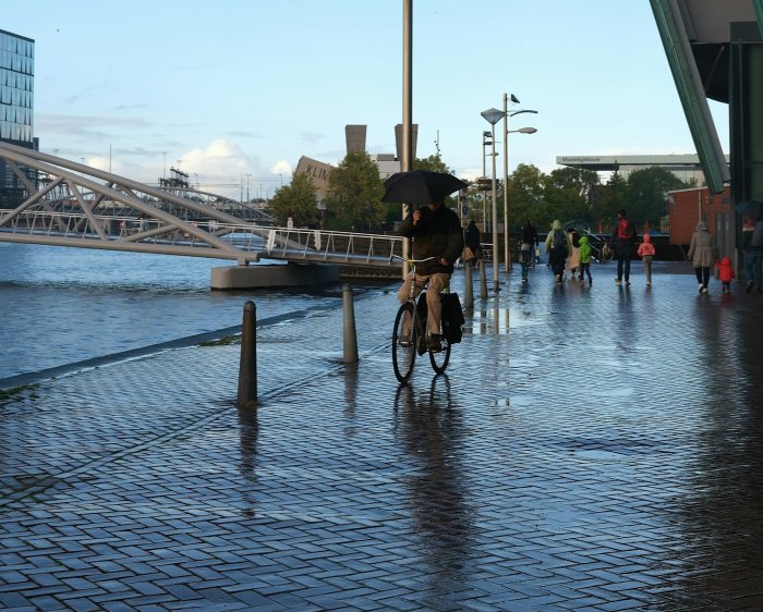 Man riding a bicycle in the rain in Amsterdam