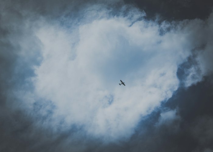 Small airplane flying through heart-shaped clouds