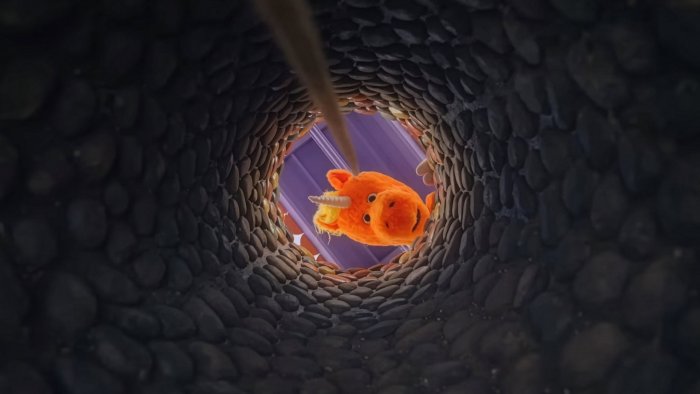 Orange puppet unicorn Buddy looking down a well