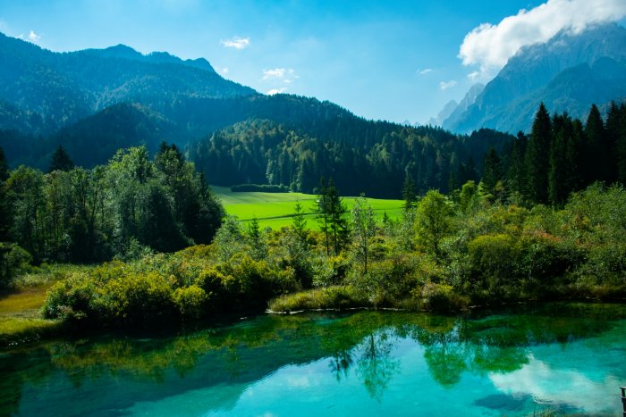 Clear turquoise lake with mountain forest reflection