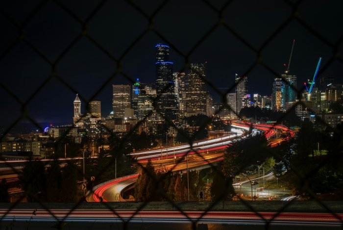 Seattle Skyline and Highway Light Trails Through Fence