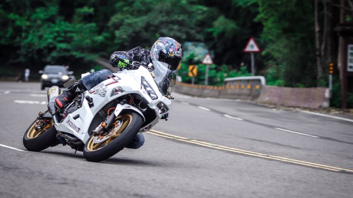 White Kawasaki Ninja Motorcycle Leaning on a Curved Road