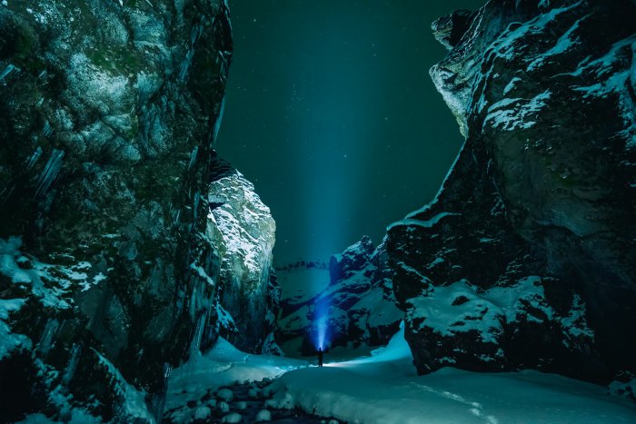 Person with flashlight in snowy canyon at night