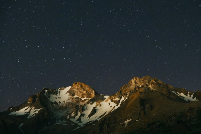 Snowy mountain peaks under a starry night sky
