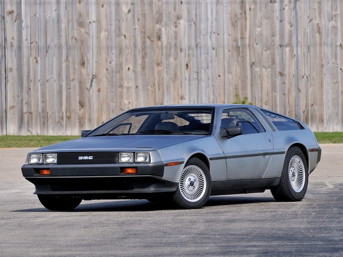1981 DeLorean DMC-12 parked in front of a wooden fence