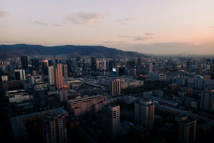Aerial view of a city skyline with mountains at sunset