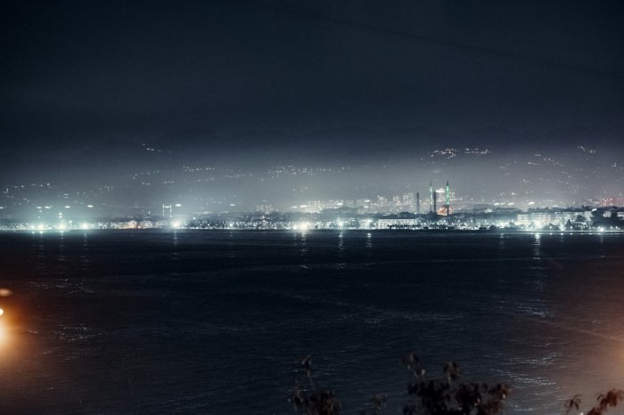 Distant city lights along a misty coastline at night
