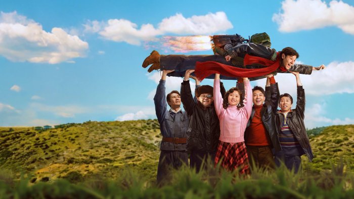 Cast of Take Off holding up a man with a jetpack
