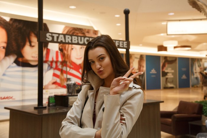 Young Woman in Trench Coat Posing in a Mall