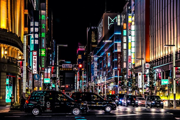 Tokyo street at night with neon signs and taxis