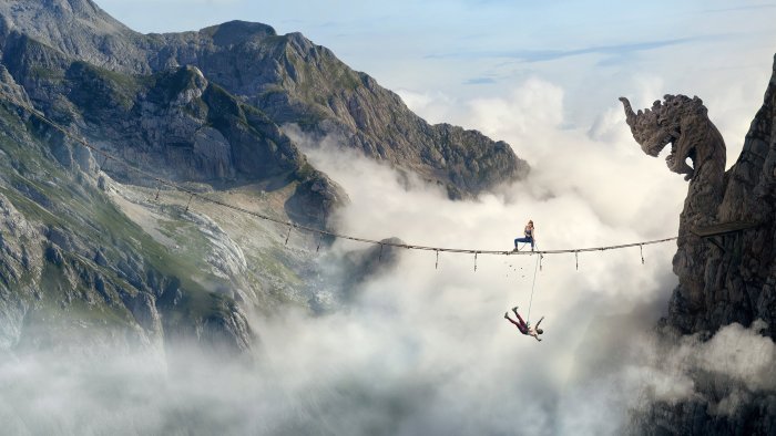 Woman on rope bridge with falling person and dragon