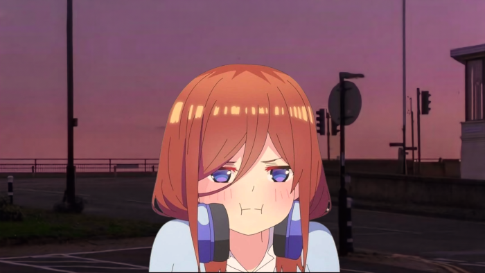 Miku Nakano with headphones on street at sunset