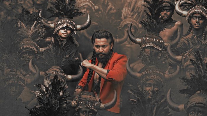 Man in red jacket with braided hair and people in tribal headdresses