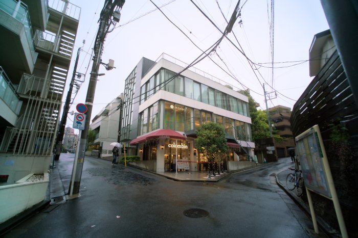 Street view of a modern building with a cafe and a person with an umbrella